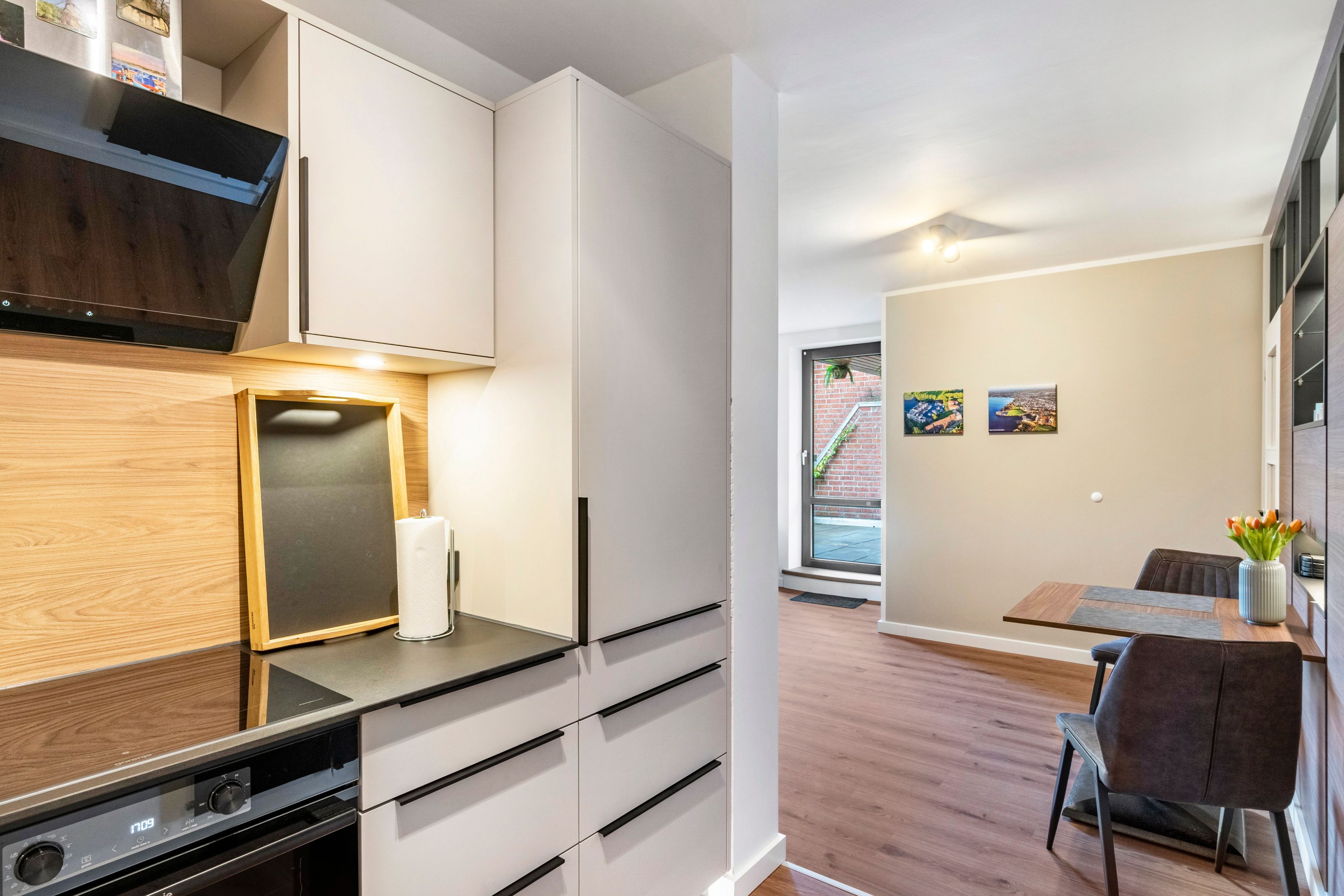 A modern kitchen with white cabinetry, a built-in oven, and a wooden countertop.