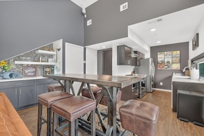 A modern kitchen with a central island, bar stools, and a refrigerator. - Welcome to your Nashville getaway! This modern 1-bedroom, 1-bath condo is located in the heart of Downtown, just steps from Broadway’s live music, incredible dining, and local attractions. Perfect for couples, solo travelers, or business guests. (Nashville)
