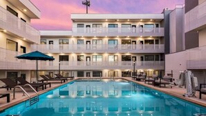 Et hotel med swimmingpool, flere balkoner og liggestole.