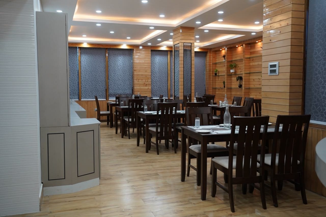 Un restaurante con paredes de paneles de madera, iluminación empotrada en el techo y varias mesas de comedor con sillas.