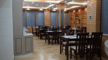 Un restaurante con paredes de paneles de madera, iluminación empotrada en el techo y varias mesas de comedor con sillas.