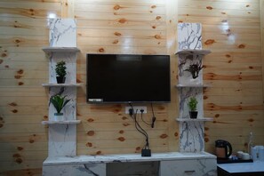 Un saló modern amb televisió de pantalla plana penjada a una paret de fusta, amb prestatgeries de marbre on hi ha plantes en testos.