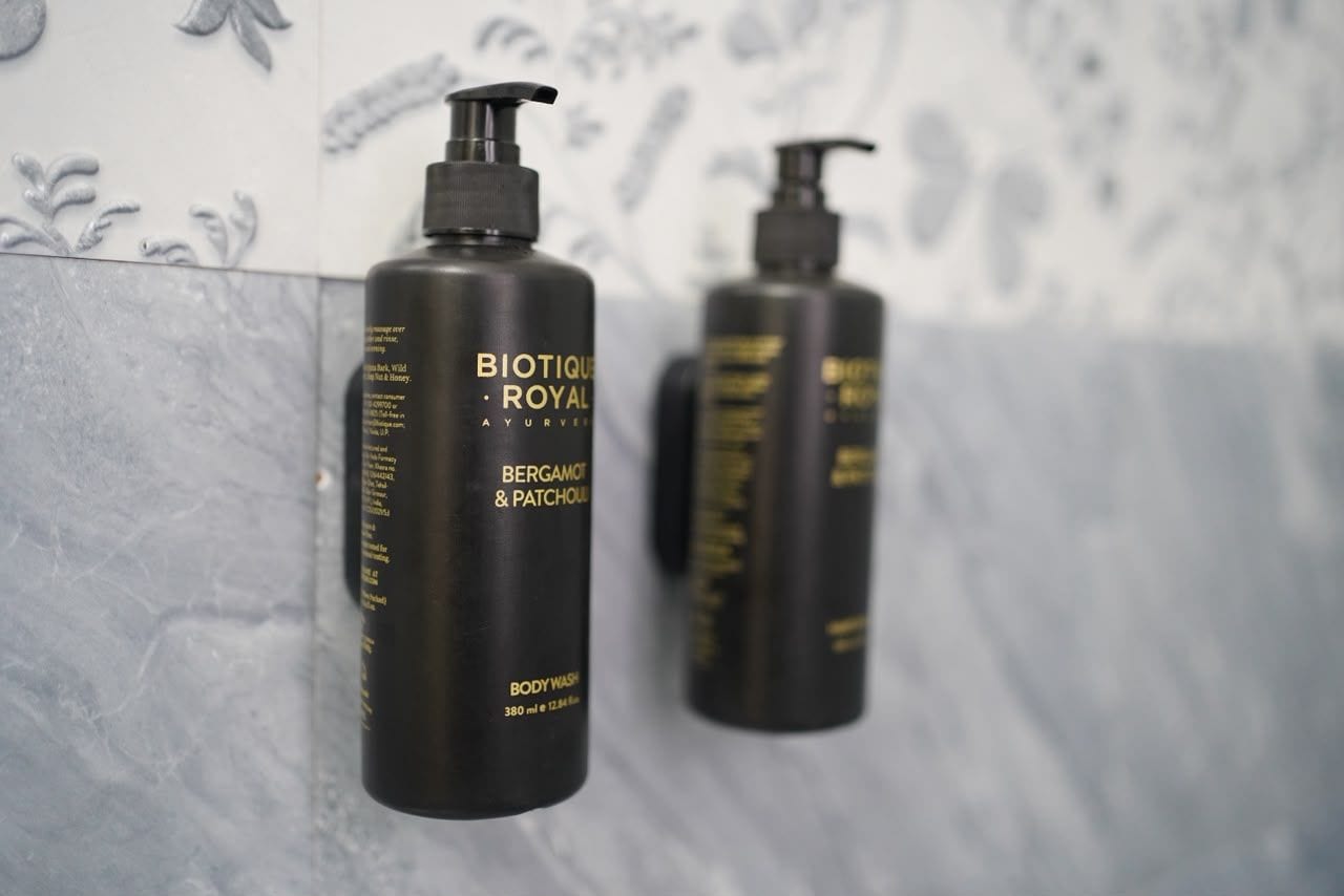 Deux flacons noirs de gel douche Biotique Royal, placés contre un mur carrelé.