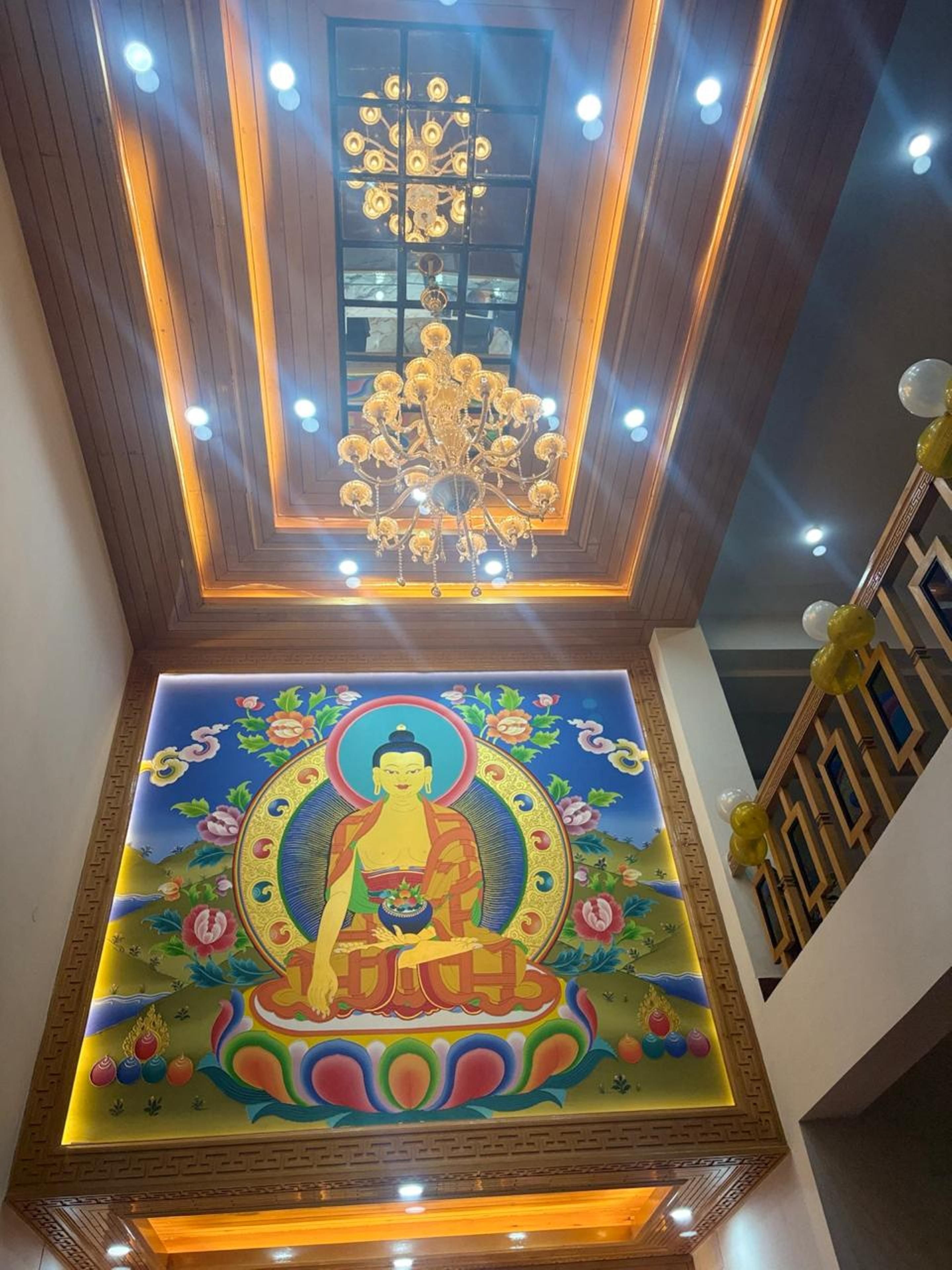 A room with a ceiling featuring a chandelier and a mural of a seated figure.
