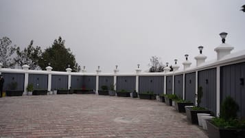 A courtyard with a paved floor, grey walls, and white decorative elements.
