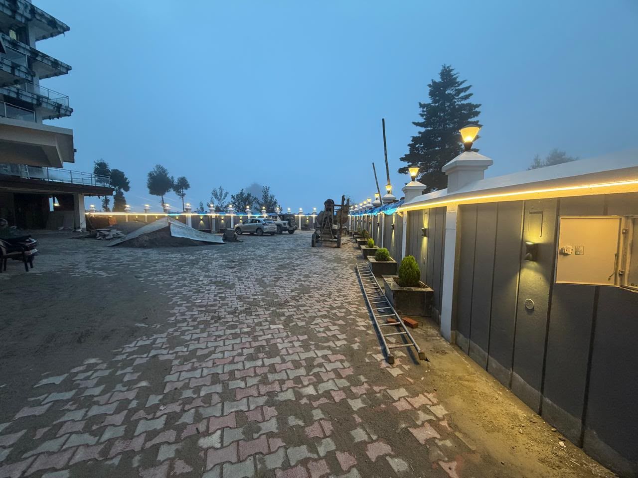 Un camino pavimentado conduce a un edificio con entrada cubierta y una serie de luces a lo largo del sendero.