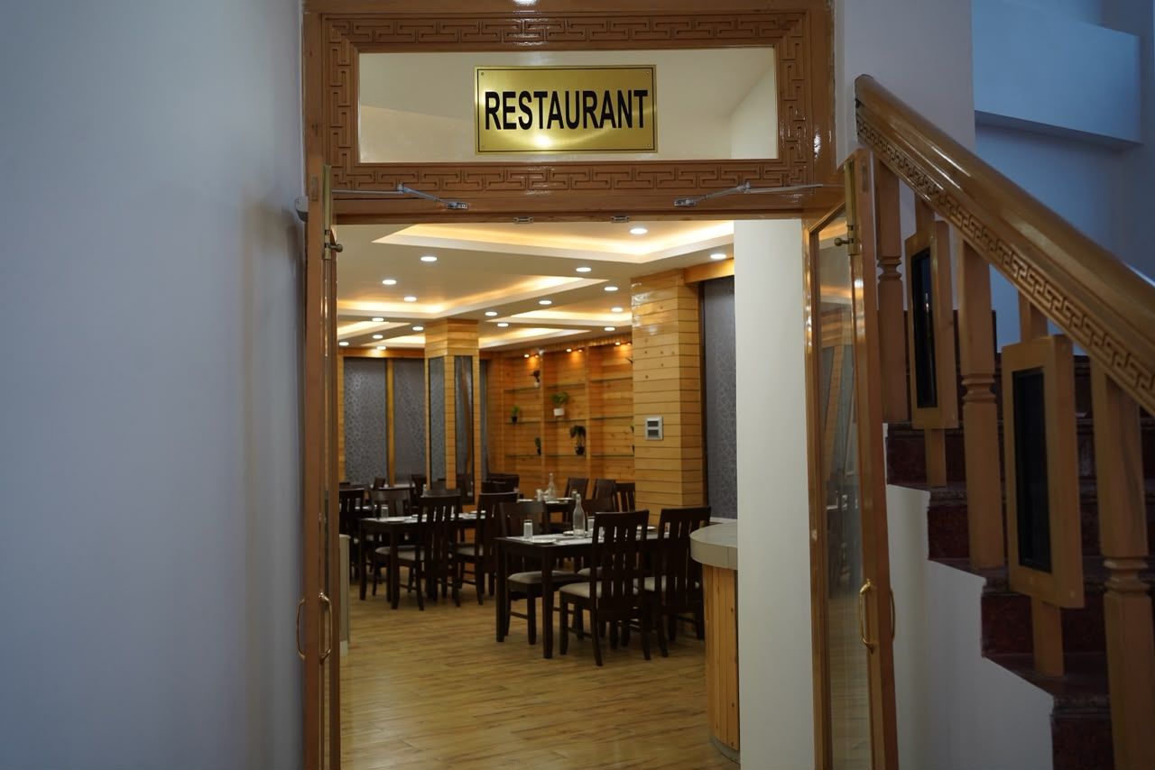 L’entrée d’un restaurant, avec une enseigne, un plancher en bois et un escalier sur la droite.