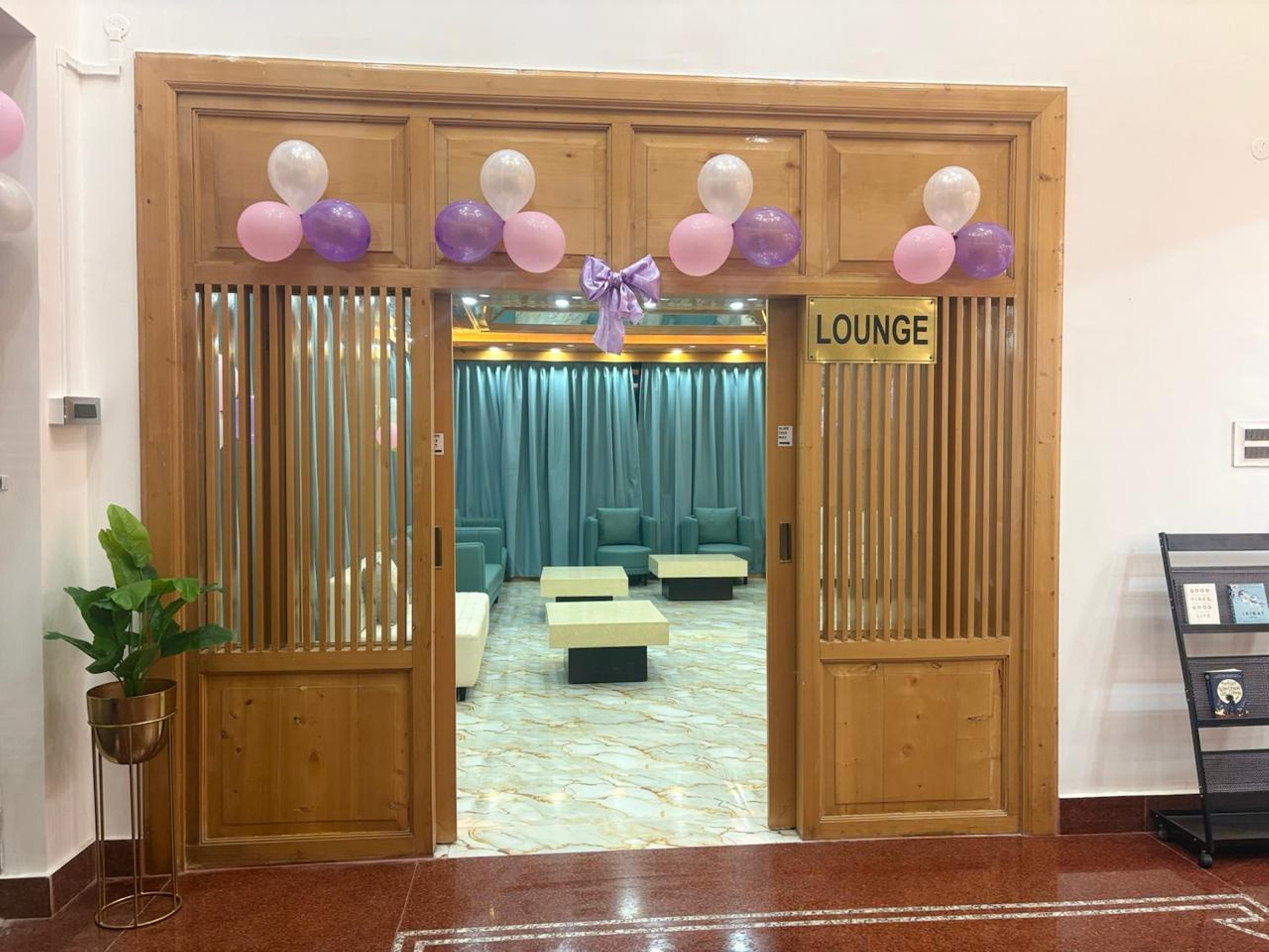 A lounge area with a wooden door, a sign reading 'LOUNGE', and a seating area with cushions and a table.