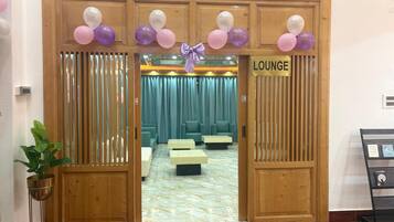 A lounge area with a wooden door, a sign reading 'LOUNGE', and a seating area with cushions and a table.