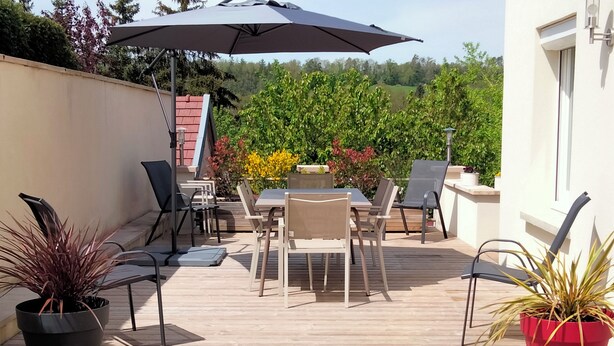 Een terras buiten met een tafel en stoelen, omringd door plantenpotten.