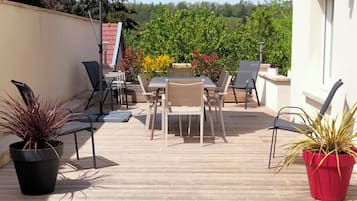 An outdoor patio with a table and chairs, surrounded by potted plants.