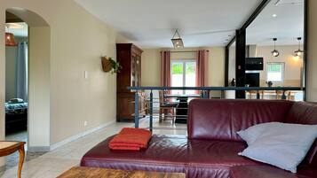 A living room with a leather sofa, a wooden coffee table, and a kitchen in the background.