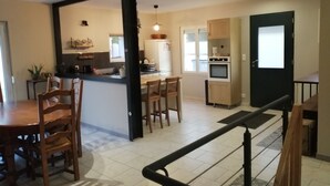 Een moderne keuken met een centraal eiland, houten stoelen en een eettafel.