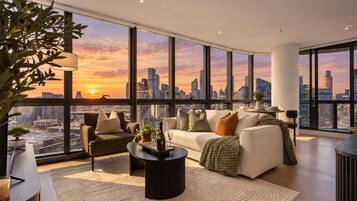 A modern living room with a city skyline view, a sofa, a coffee table, and a potted plant.