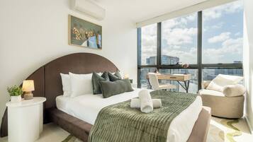 A modern hotel room with a large bed, a desk, and a view of the city.