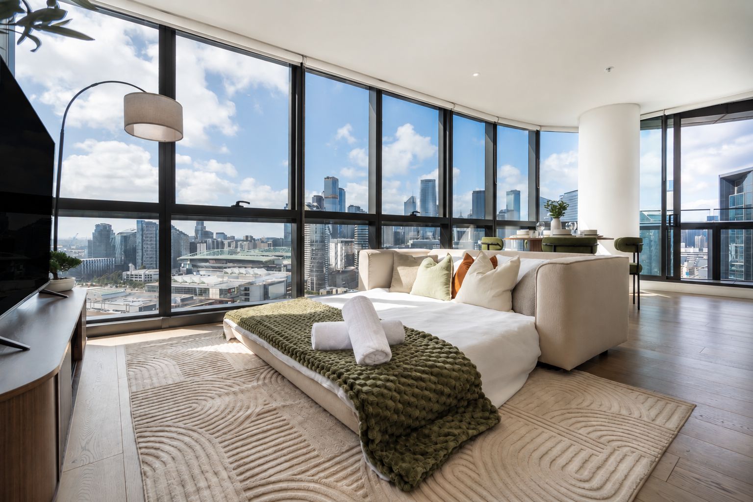 Ein modernes Schlafzimmer mit Blick auf die Stadt, inklusive Bett, Schreibtisch und großem Fenster.