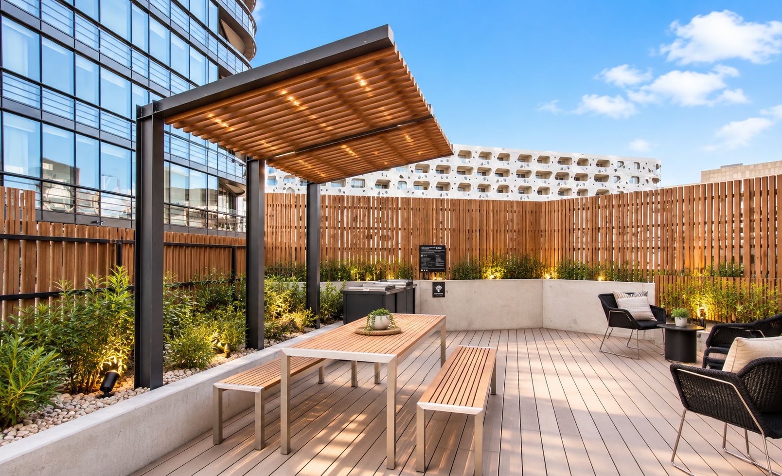 An outdoor patio with wooden flooring, a table, chairs, and a pergola.