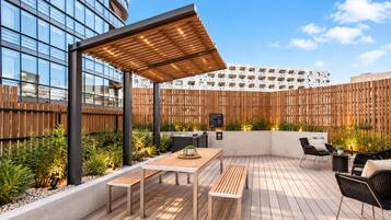 An outdoor patio with wooden flooring, a table, chairs, and a pergola.
