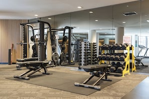A modern gym with various exercise equipment, including weight machines and free weights. - Skyline Views | 2 Carpark | Pool, Gym & Spa | Marvel Stadium (Docklands)