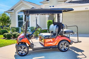 A golf cart parked in a driveway with a house in the background. - Summer Breeze - 3/3 w/ 4-Seat Golf Cart in The Villages - St Catherine (St Catherine, The Villages)