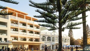 Hotel com vários andares, varandas, área externa para sentar e uma palmeira.