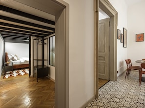 A hallway with a bed, a wardrobe, and a dining area with chairs and a table. - Old Town Mezzanine Apartment (Kraków)