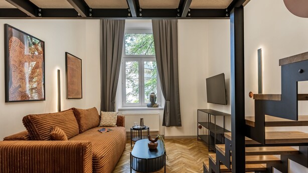 Una sala de estar moderna con un sofá, una mesa de centro, un televisor y una escalera.