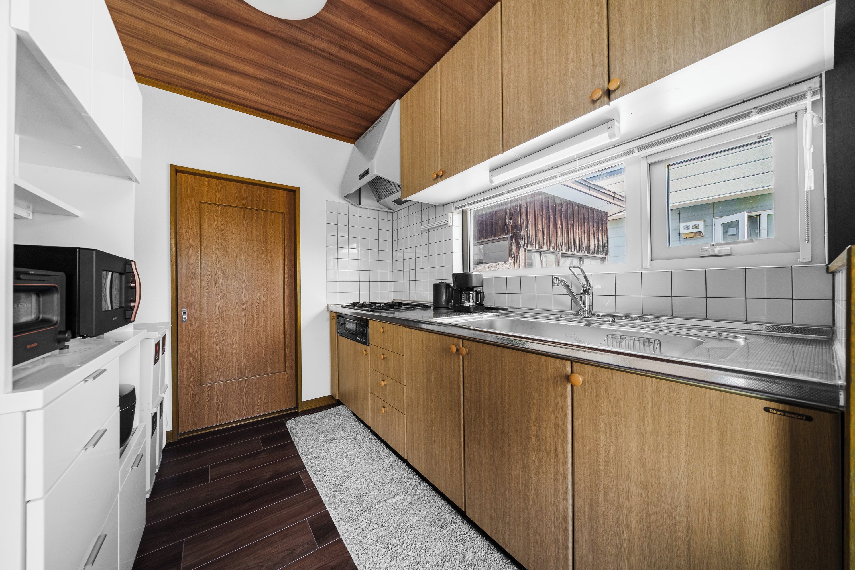 A modern kitchen with wooden cabinets, a stainless steel countertop, and a built-in oven.