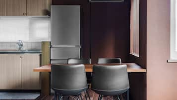 Una cocina moderna con refrigerador empotrado, una mesa de comedor con sillas y un ventanal con persianas.