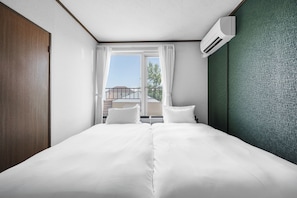 Una habitación de hotel con una cama, dos almohadas, una ventana con cortinas y un equipo de aire acondicionado.