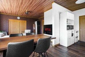 Una cocina moderna con microondas integrado, refrigerador y televisión de pared mostrando 'NETFLIX'.