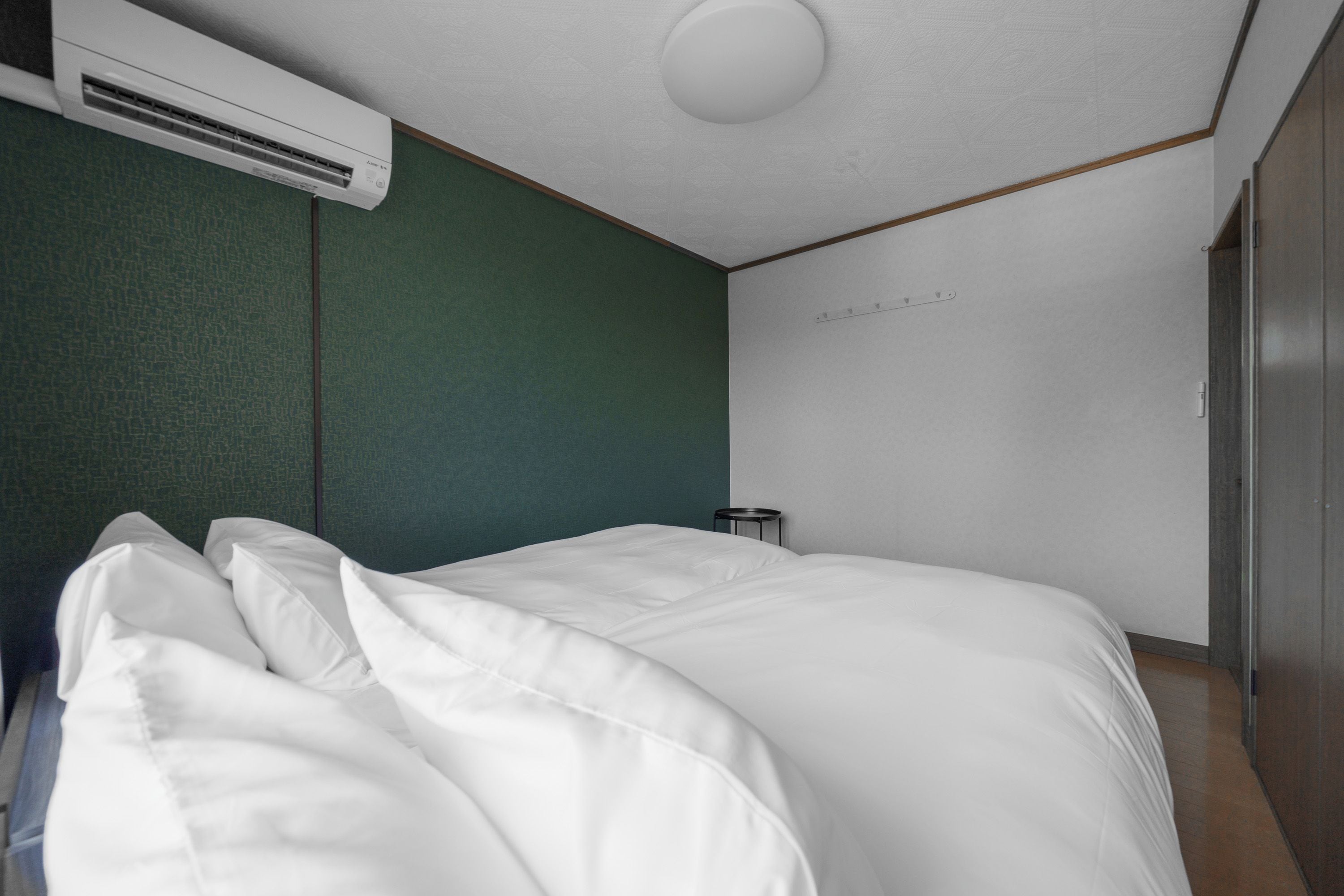 Un dormitorio con una cama, una mesita de noche, un aire acondicionado y un armario.