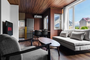 Una sala de estar moderna con sofá, sillones, televisor y un comedor con mesa y sillas.