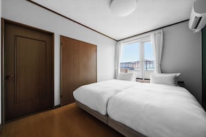 Una habitación de hotel con una cama grande, un armario, una ventana con cortinas y un equipo de aire acondicionado.