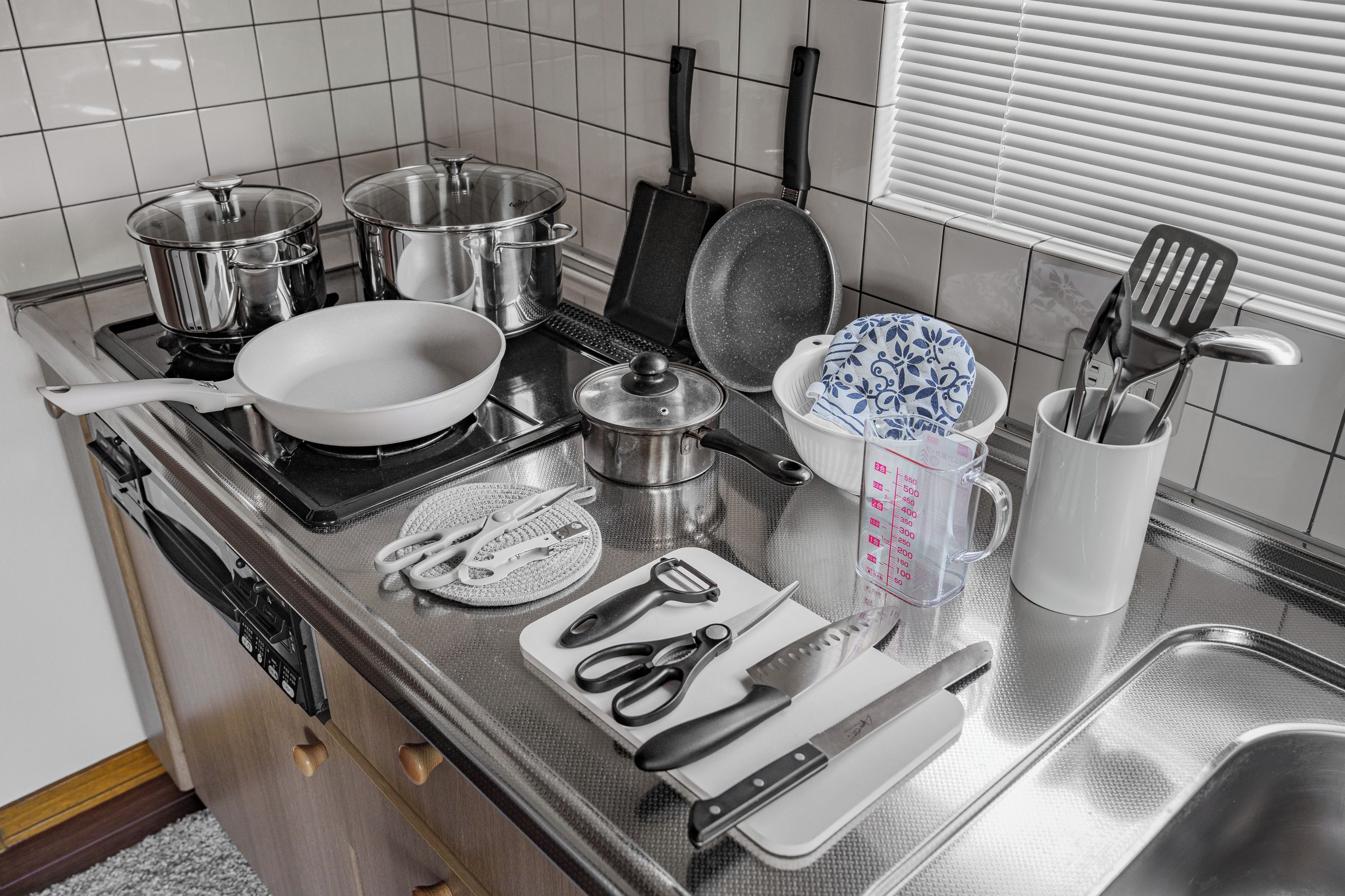 A kitchen with stainless steel appliances, including a stove, pots, pans, and a sink.
