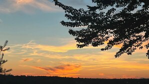 Een vredig uitzicht over een meer bij zonsondergang, met bomen en een rustig wateroppervlak.