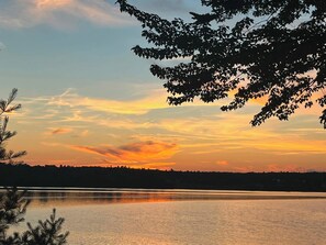 Una vista serena sobre un lago al atardecer, con árboles y una superficie acuática tranquila.