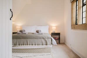 Ein Schlafzimmer mit einem Bett, zwei Nachttischlampen, einem Nachttisch und einem Fenster.