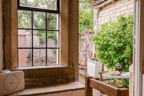 Ein Zimmer mit Fensterblick auf einen Garten, ein Tisch mit Teekanne und ein Stuhl.