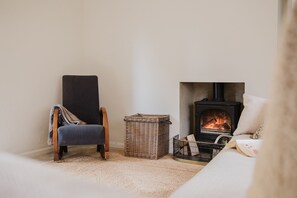 Ein gemütliches Zimmer mit Kamin, einem Sessel und einem Korb.