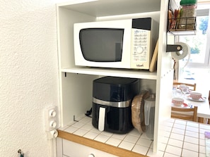 Een keuken met een magnetron op het bovenste plankje en een koffiezetapparaat op het onderste plankje.