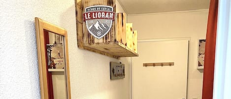 Un pasillo con un armario de madera, un espejo y una puerta con un tapete que dice '¡HELLO!'.