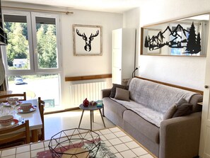 Ein gemütliches Wohnzimmer mit einer Couch, einem Esstisch gedeckt mit Geschirr und Kunstwerken an den Wänden.