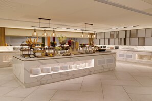 A modern kitchen with a marble countertop, a central island with food displays, pendant lighting, and a tiled backsplash. - Lemon Tree Premier, Jabalpur (Jabalpur)