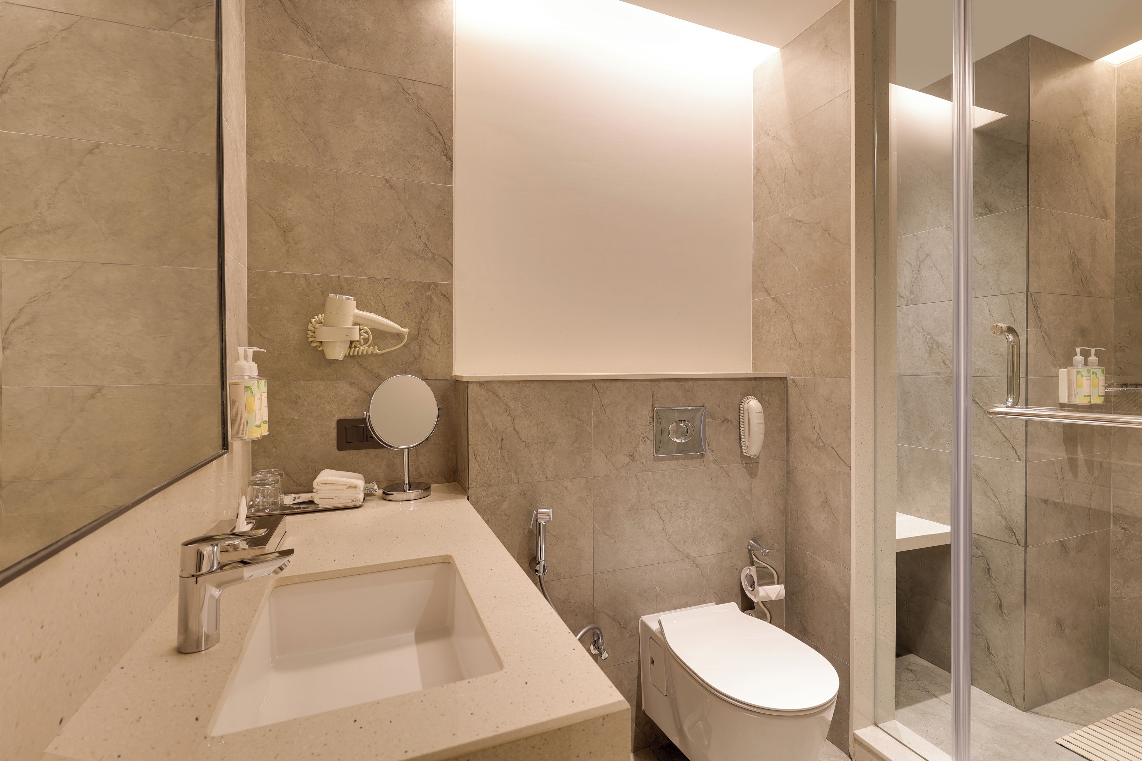 A modern bathroom with a large mirror, a sink, a toilet, and a shower area.