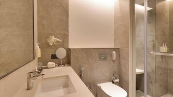 A modern bathroom with a large mirror, a sink, a toilet, and a shower area.