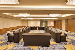 Un salón de conferencias con una mesa larga, sillas y piso alfombrado.