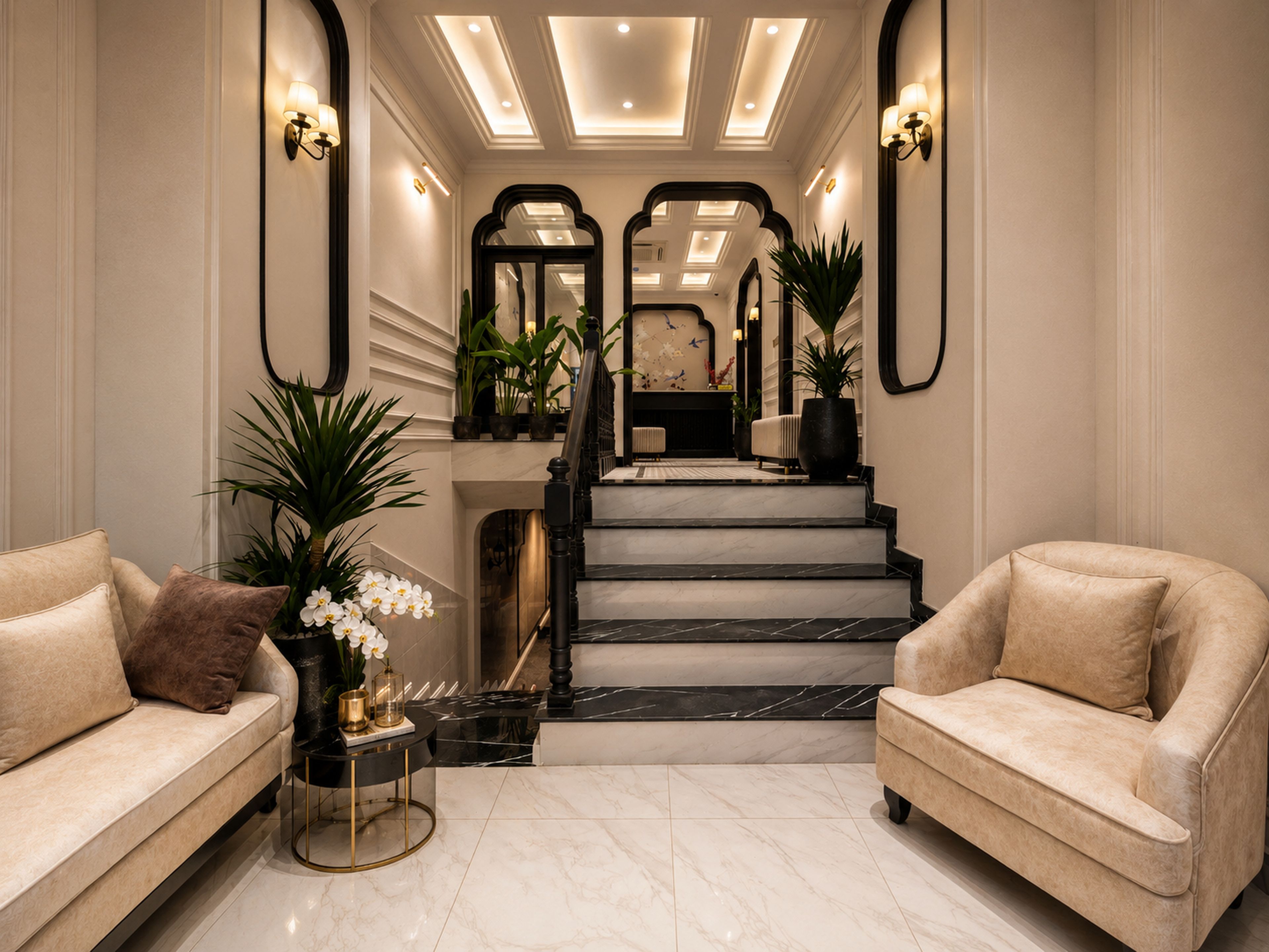 En rummelig lobby med en marmortrappe, to sofaer og en reception.