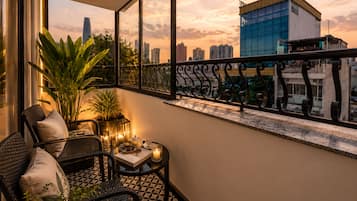 Varanda com vista para o horizonte urbano, um vaso de planta e uma mesa com uma vela.
