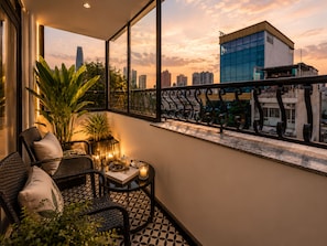 Varanda com vista para o horizonte urbano, um vaso de planta e uma mesa com uma vela.